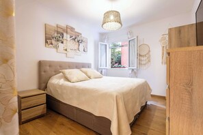 A bedroom with a bed, bedside tables, a window, and wall decorations. - Charming ground floor villa apartment with a heated swimming pool (Cers)