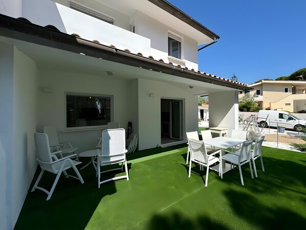 A patio with white furniture and a green artificial turf.