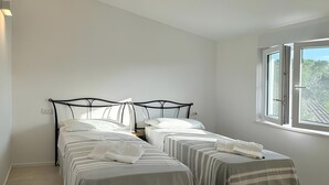 Un dormitorio con dos camas, una ventana y un interruptor de luz en la pared.