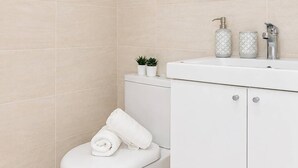 Ein modernes Badezimmer mit Toilette, Waschbecken und Spiegel.
