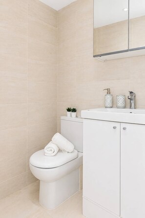 Ein modernes Badezimmer mit Toilette, Waschbecken und Spiegel.