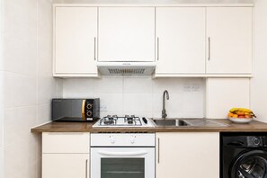 Een kleine keuken met een gasfornuis, oven, vaatwasser en een magnetron.