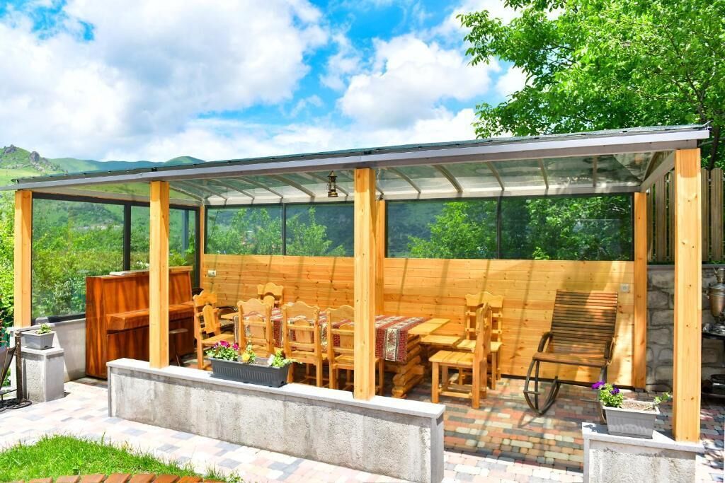 Un espace extérieur abrité, aménagé avec du mobilier en bois et offrant une vue sur le paysage environnant.