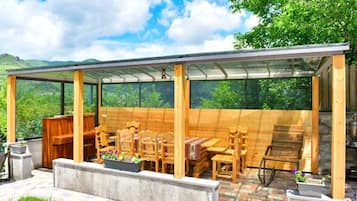 Ein überdachter Außenbereich mit Holzmöbeln und Blick auf die umliegende Landschaft.