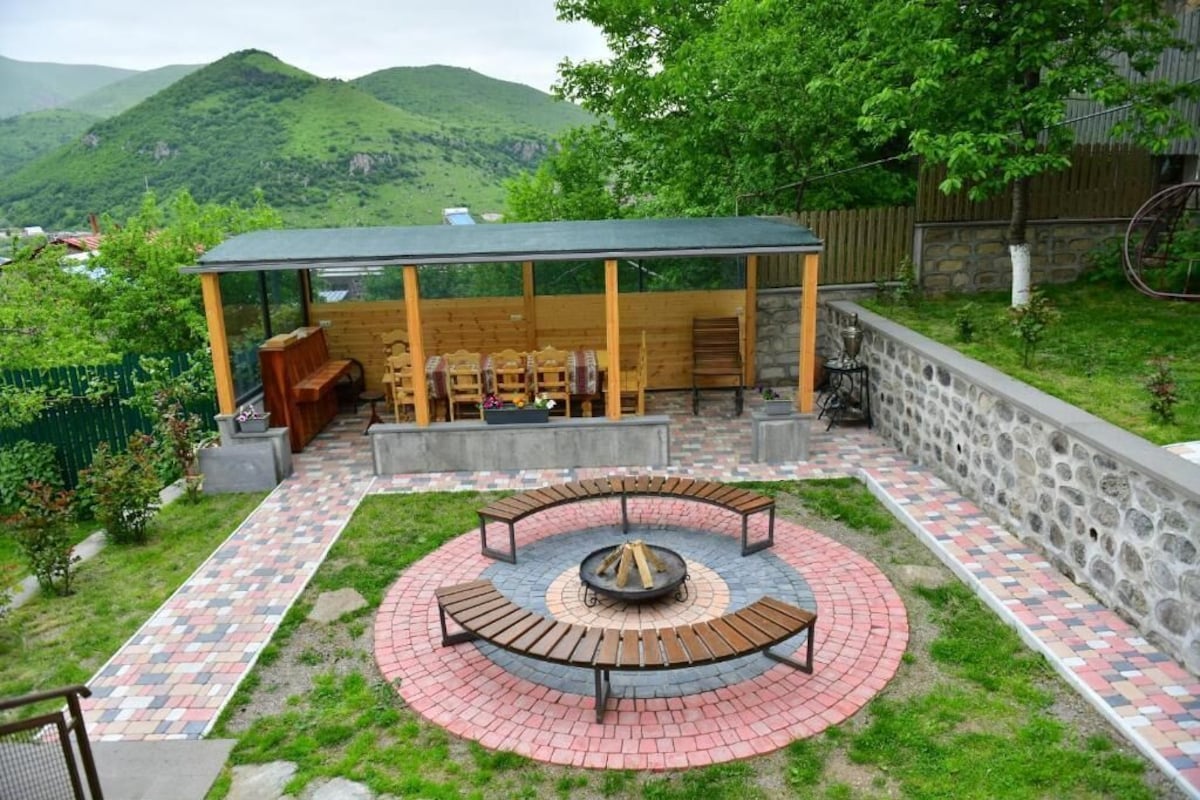 Un espacio de estar al aire libre cubierto con un brasero, rodeado por un patio de ladrillo decorativo.