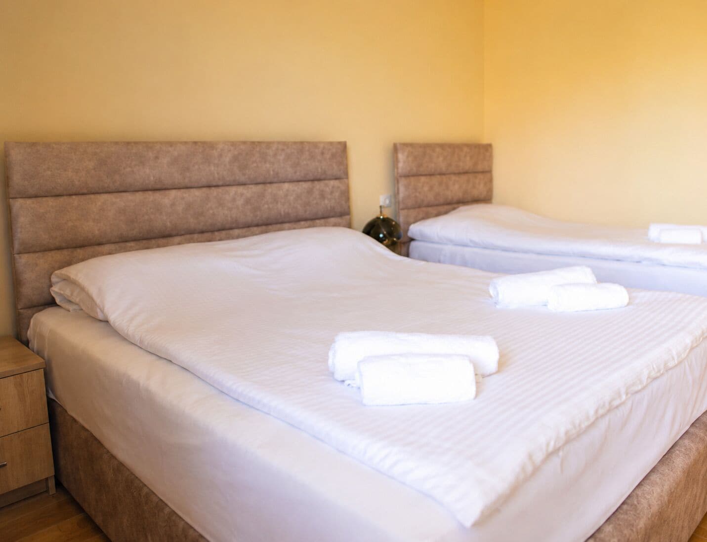 Ein Hotelzimmer mit zwei Betten, jeweils mit Kopfteil und weißer Bettwäsche.