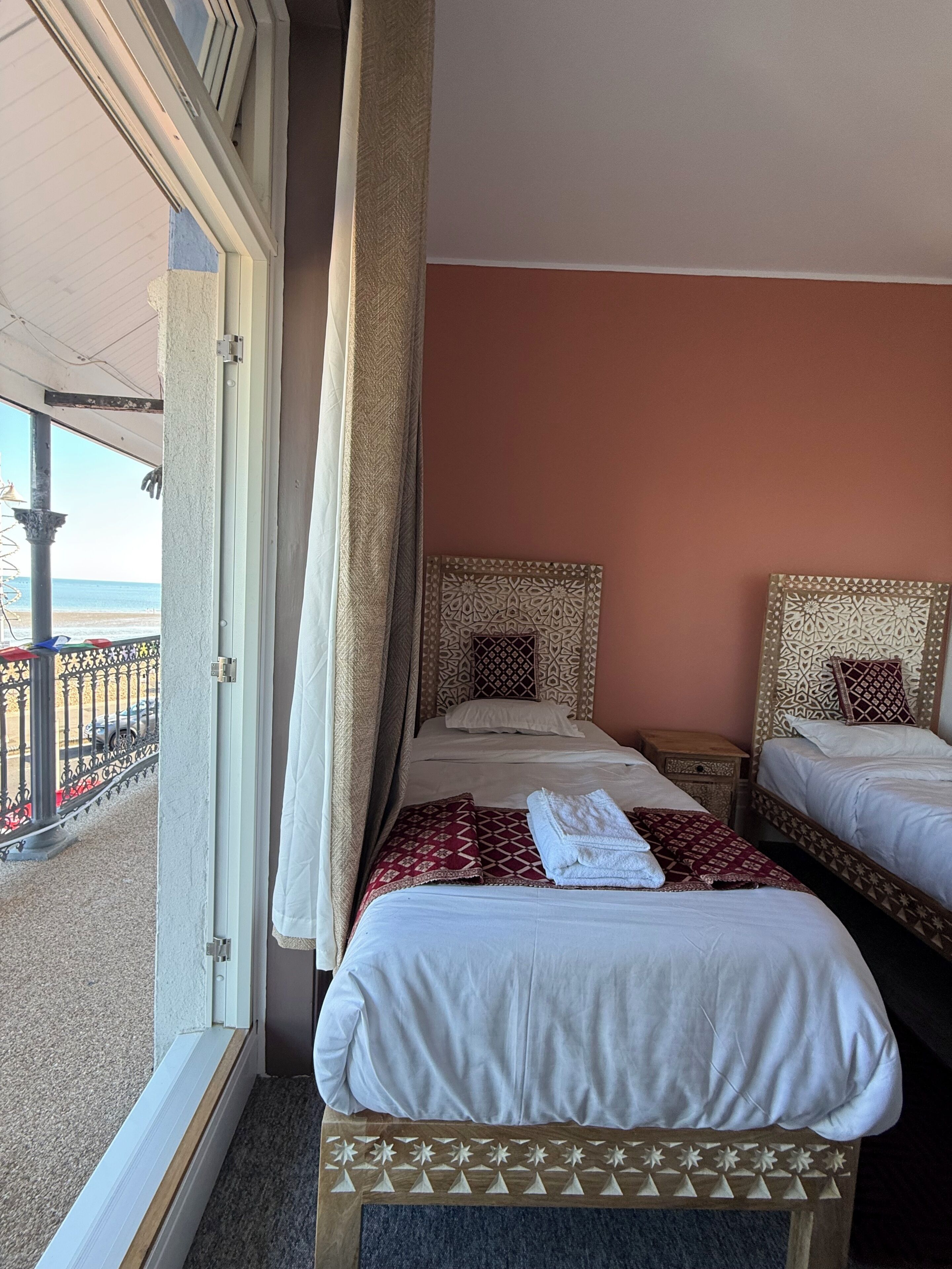 A hotel room with two beds, a balcony, and a view of the beach.