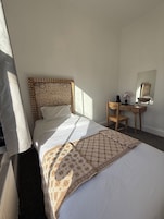 Habitación de hotel con cama, escritorio, silla, espejo y radiador.