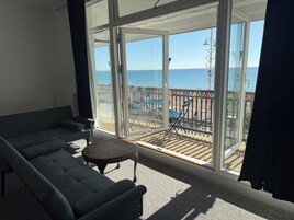 Una habitación con sofá, una mesita y vista al mar a través de amplios ventanales.