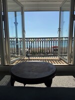Un balcón con mesa, barandilla y vista al mar.