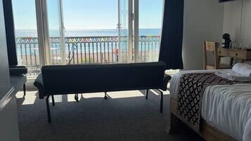 A hotel room with a bed, a bench, a desk, and a TV.