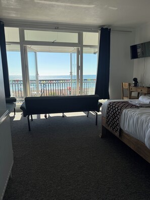 A hotel room with a bed, a bench, a desk, and a TV. - The Carlton Hotel (Bognor Regis)