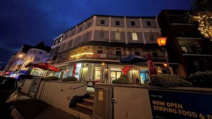 A multi-story building with a ground-level restaurant and a sign indicating it is now open serving food and drinks.