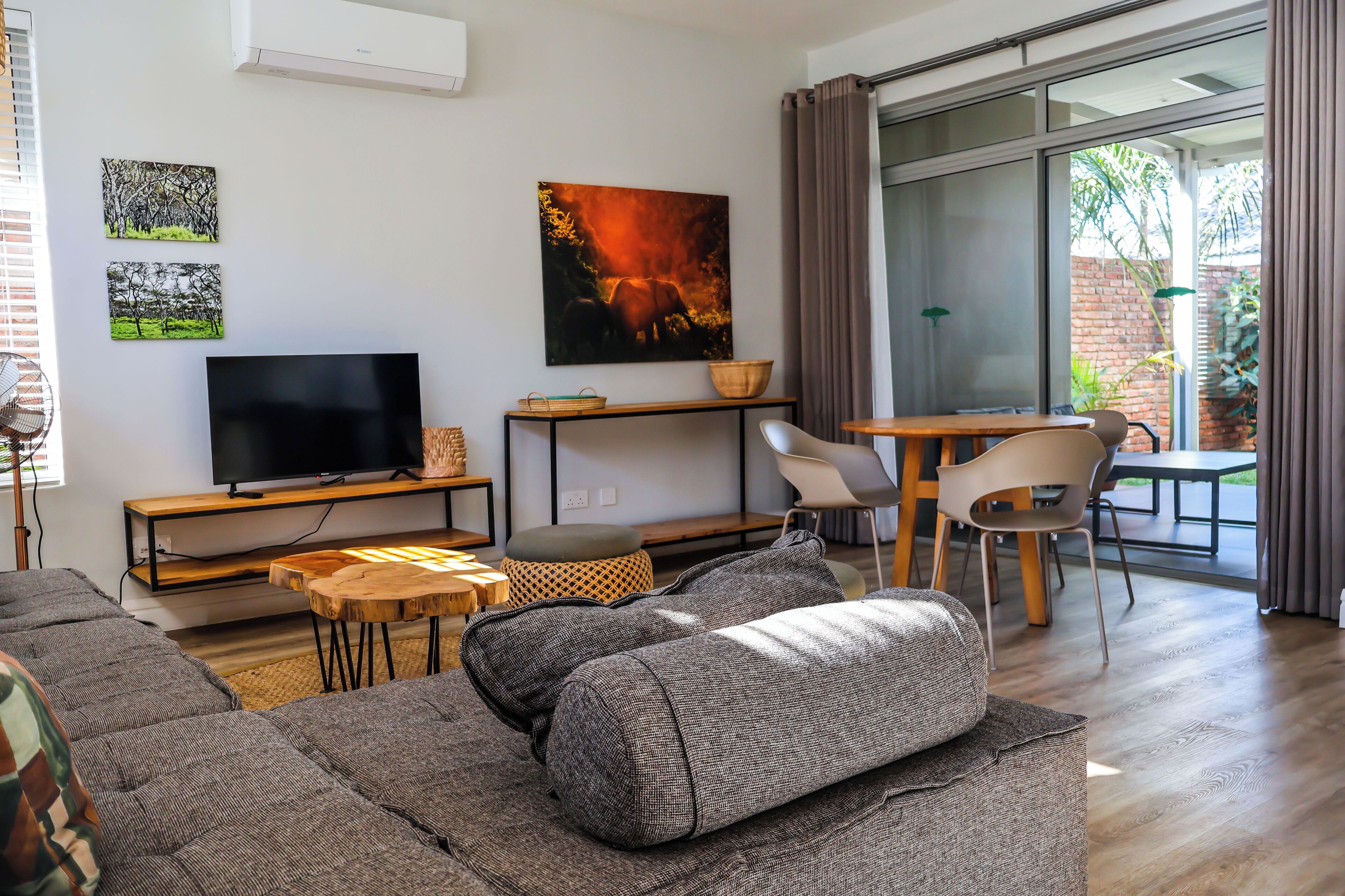 Ein modernes Wohnzimmer mit Flachbildfernseher, einer Couch, einem Couchtisch und einem Essbereich mit Stühlen.