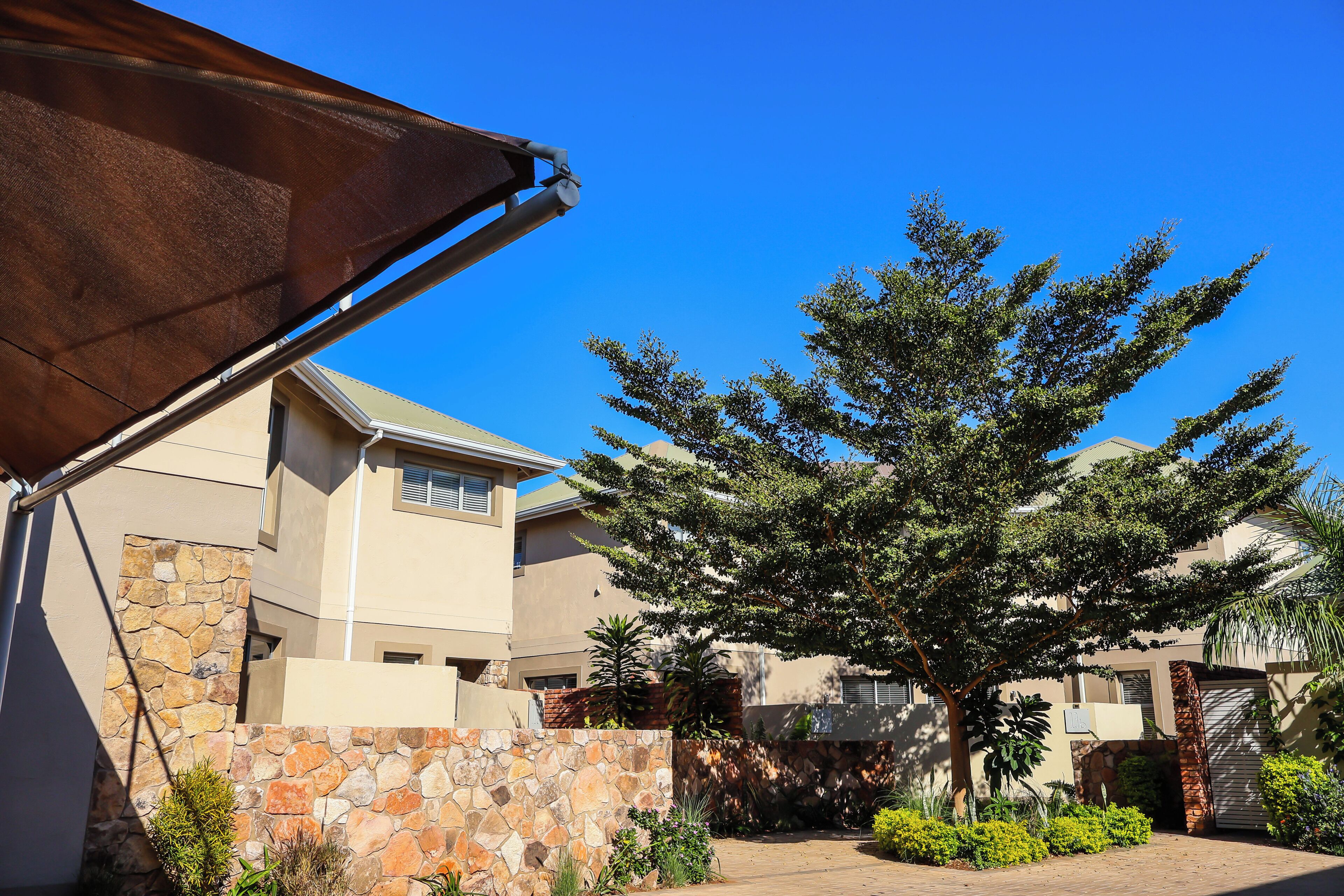 A residential area with a stone wall, a tree, and a building with a tiled roof.