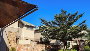 A residential area with a stone wall, a tree, and a building with a tiled roof.