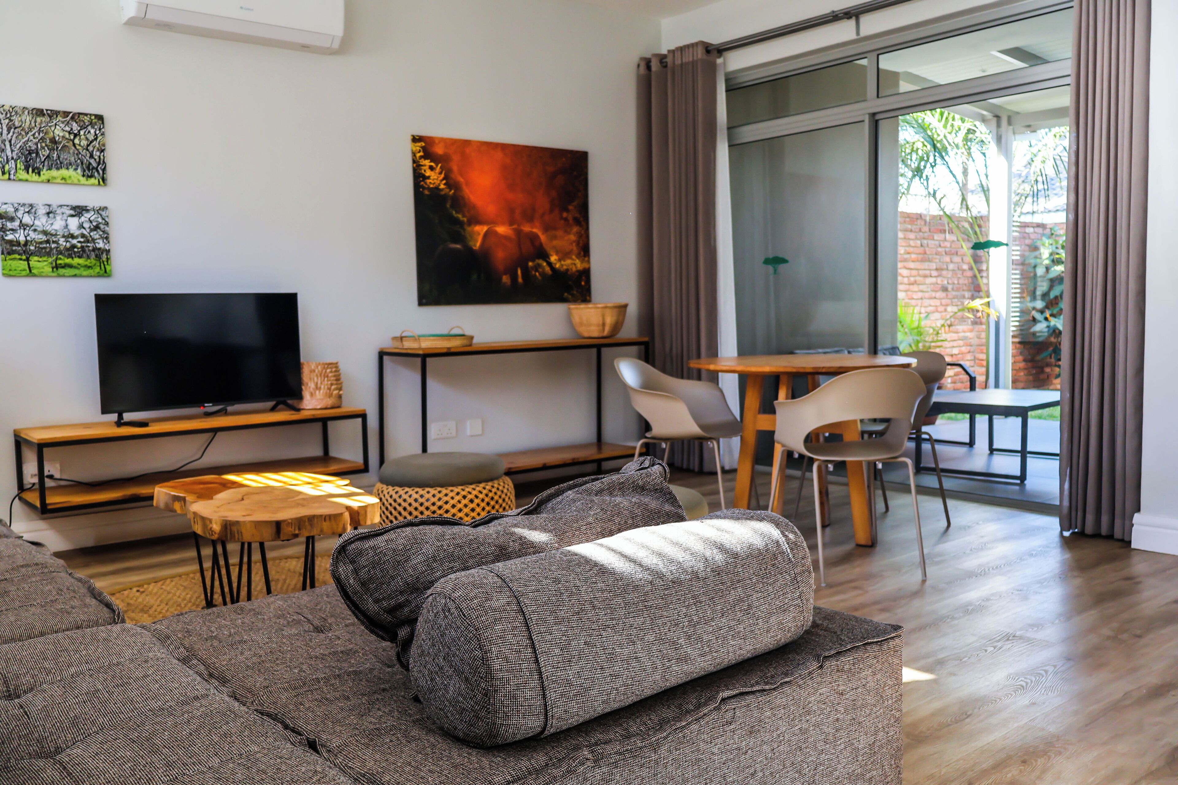Uma sala de estar moderna com uma televisão de tela plana, um sofá, uma mesa de centro e um espaço de jantar com cadeiras e uma mesa.