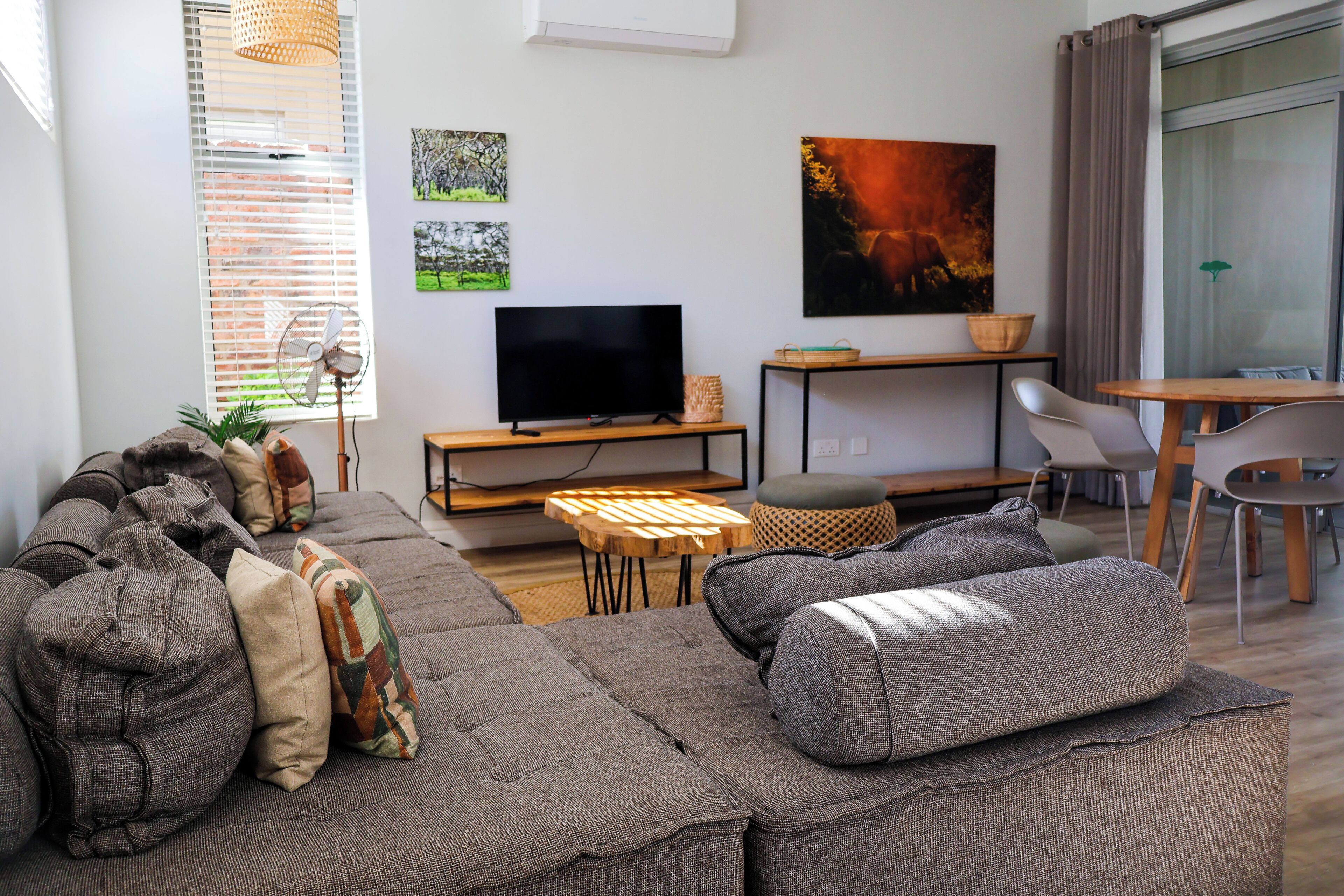 A modern living room with a sectional sofa, a flat-screen TV, and a dining area with a table and chairs.