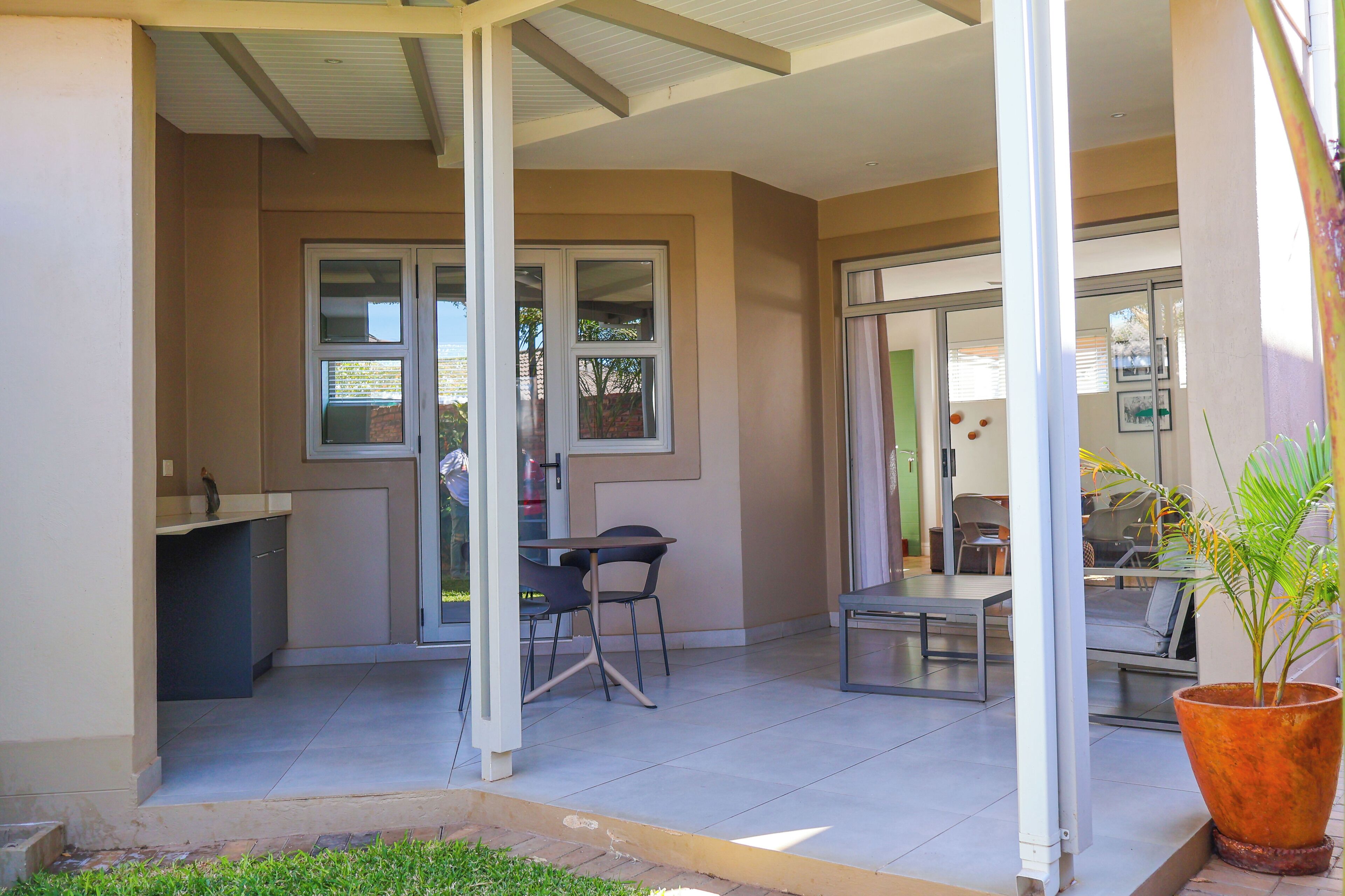 An outdoor patio area with a dining table and chairs, a small seating area, and a potted plant.