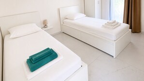 A hotel room with two single beds, a wardrobe, and a window with curtains. - New three-room apartment in a quiet neighborhood, Valescure district (Saint-Raphaël)