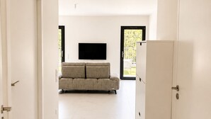 A modern interior with a sofa, a flat-screen TV, and a refrigerator. - New three-room apartment in a quiet neighborhood, Valescure district (Saint-Raphaël)