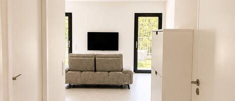 Een modern interieur met een bank, een flatscreen televisie en een koelkast.