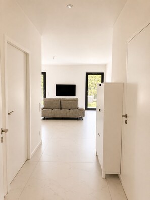Et moderne interiør med en sofa, et fladskærms-tv og et køleskab.