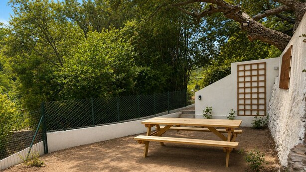 A picnic table in a garden area with a white wall and a wooden fence. - New three-room apartment in a quiet neighborhood, Valescure district (Saint-Raphaël)