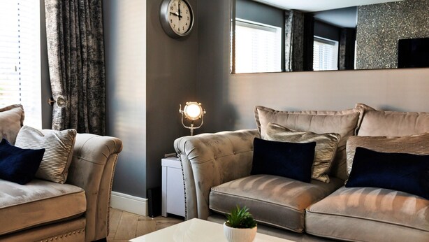 Ein modernes Wohnzimmer mit zwei Sofas, einem Couchtisch, einer Wanduhr und einer kleinen Pflanze.