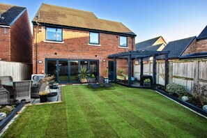 A residential backyard with a lawn, outdoor furniture, and a brick house. - Beach House Near Northumberland' (Blyth)