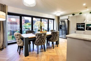 A modern kitchen with a dining area, large windows, and a view of the backyard. - Beach House Near Northumberland' (Blyth)