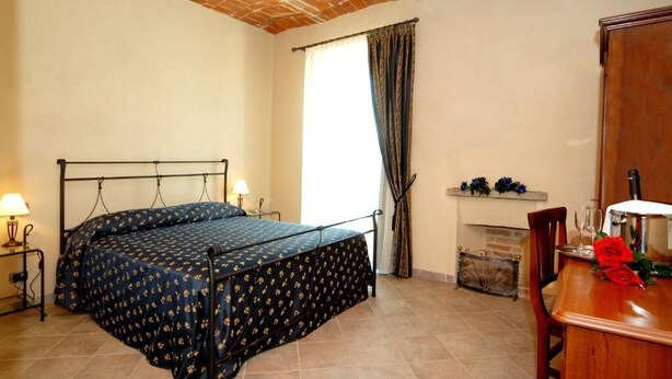 Una camera da letto con un letto, comodini, un camino e un tavolo da pranzo.