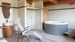 Un bagno moderno con doccia, vasca idromassaggio e una poltrona.