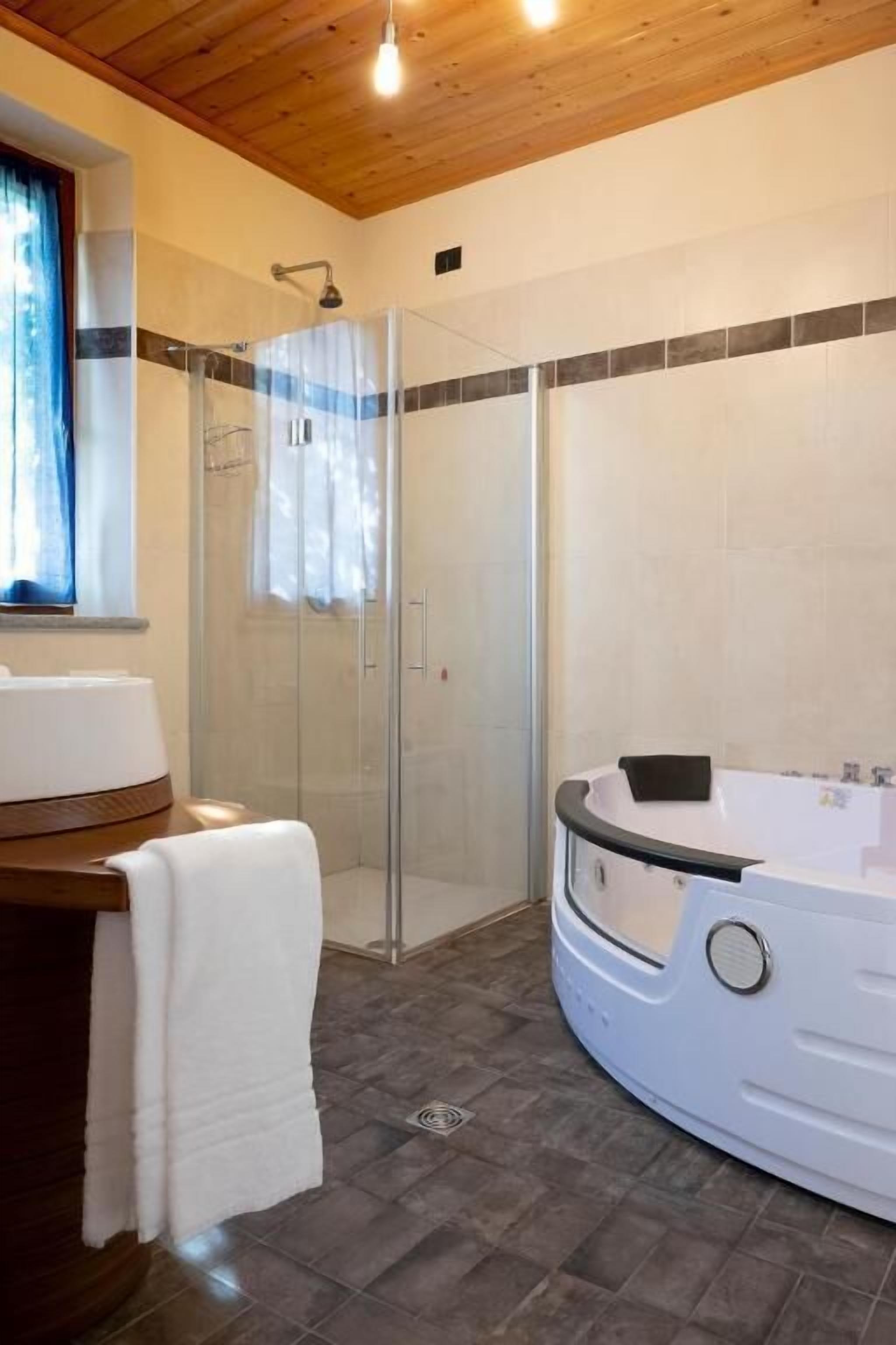 Un baño con ducha de vidrio, una bañera blanca y un tocador de madera.