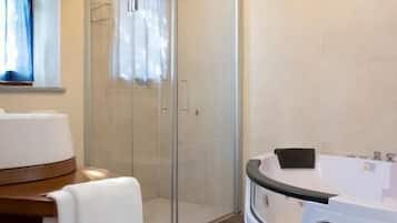Un baño con ducha de vidrio, una bañera blanca y un tocador de madera.