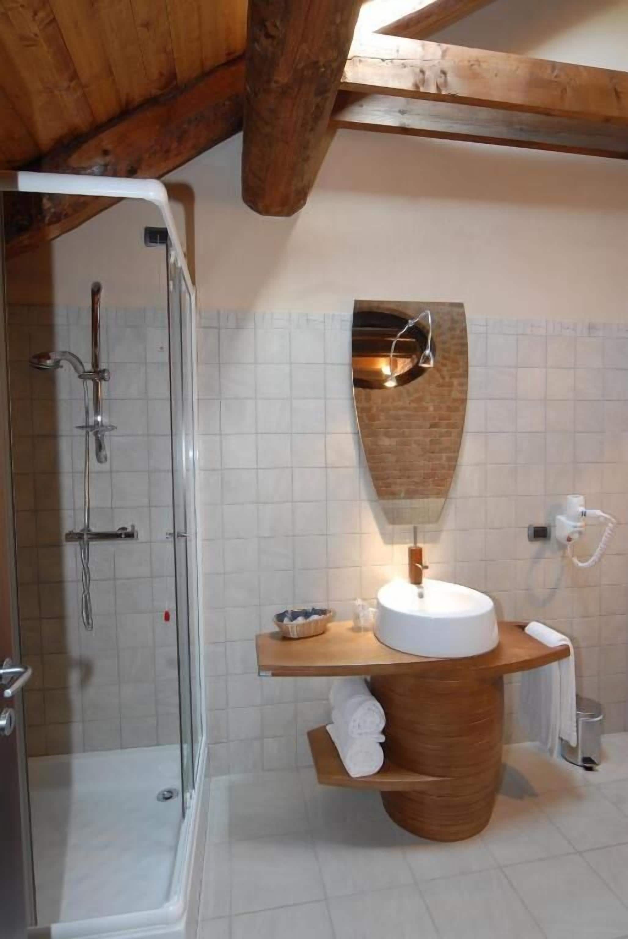 A bathroom with a glass shower enclosure, a wooden vanity with a sink, and a towel rack.