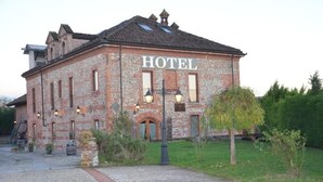 Un edificio in mattoni con la scritta 'HOTEL' sulla facciata, un piccolo ingresso e un vialetto che conduce alla porta.