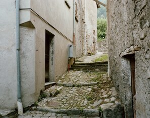 A narrow cobblestone alleyway between buildings with a metal door and a small step leading to a higher level. - Il Cortile di Nesso (Nesso)