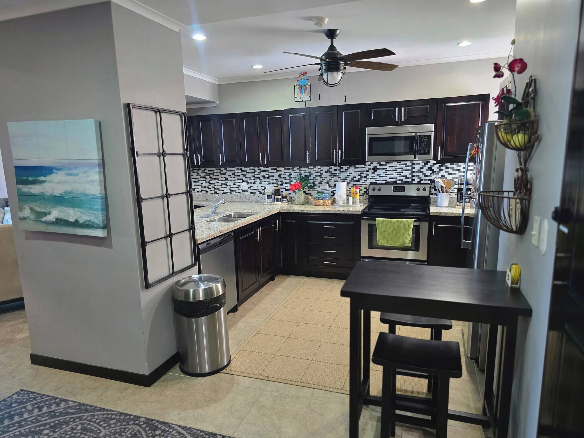 A modern kitchen with dark cabinets, a microwave, an oven, and a dining area with a table and chairs.