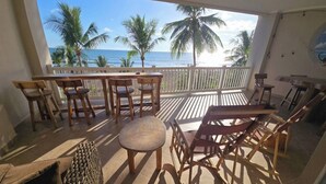 A balcony with wooden furniture, a view of the ocean, and palm trees. - Amazing Oceanfront With Access Crocs Resort (Jacó)