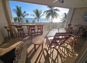 A balcony with wooden furniture, a view of the ocean, and palm trees. - Amazing Oceanfront With Access Crocs Resort (Jacó)