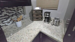 A small kitchen with a granite countertop, a coffee maker, a toaster, and a spice rack. - Amazing Oceanfront With Access Crocs Resort (Jacó)