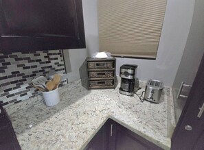A small kitchen with a granite countertop, a coffee maker, a toaster, and a spice rack. - Amazing Oceanfront With Access Crocs Resort (Jacó)