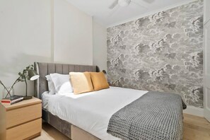 Ein Schlafzimmer mit Bett, Nachttisch und einer Wand mit strukturierter Oberfläche.