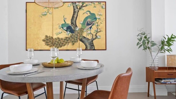 A dining area with a round table set for four, surrounded by brown leather chairs. A traditional painting of peacocks on a tree hangs above the table. - 44 Adelaide Street (Surry Hills)