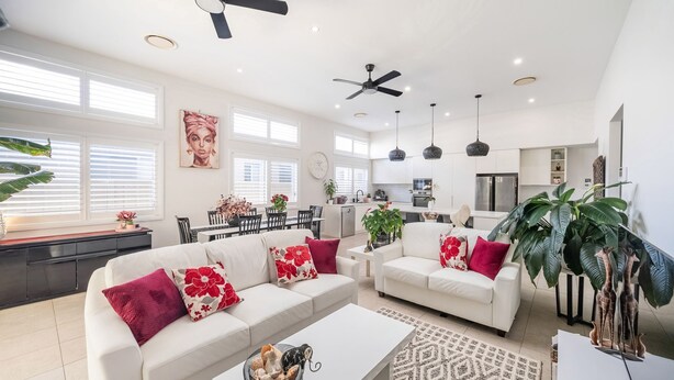 A spacious living area with a white sofa set, a coffee table, and a dining area with a white table and chairs. - Corlette Coastal Haven (Corlette)