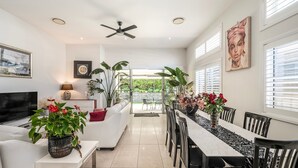 A modern interior with a dining area, seating, and a television. - Corlette Coastal Haven (Corlette)