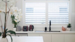 A kitchen with a window, a sink, and various appliances. - Corlette Coastal Haven (Corlette)