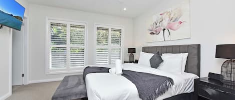 A bedroom with a bed, a ceiling fan, a TV, and a painting.