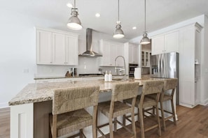 A modern kitchen with white cabinets, a granite countertop, and a stainless steel refrigerator.